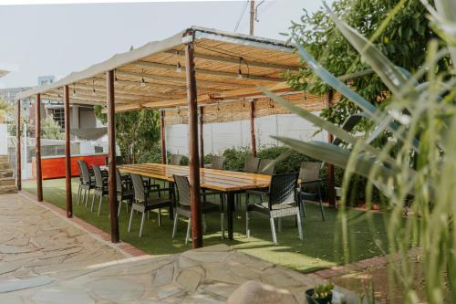 a wooden pergola with a wooden table and chairs at Hotel Uhland in Windhoek