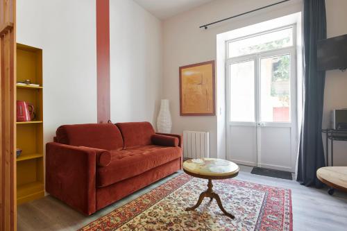 a living room with a red couch and a table at Villa Po'Strophe - Bâtiment classé avec piscine in Clisson