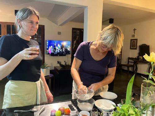 two women standing in a kitchen preparing food at Pekoetrails Hantana Homestay in Kandy