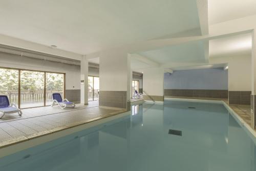 - une piscine avec 2 chaises bleues dans un bâtiment dans l'établissement Résidence Odalys Pra Sainte Marie, à Vars