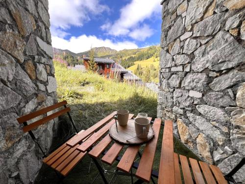 une table de pique-nique en bois avec deux tasses dessus dans l'établissement Esprit chalet, cosy et piscine, à La Plagne Tarentaise