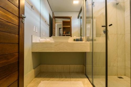 une salle de bain avec un lavabo et une douche en verre dans l'établissement Apto 110 Taiti Villas BobZ, à Barrinha