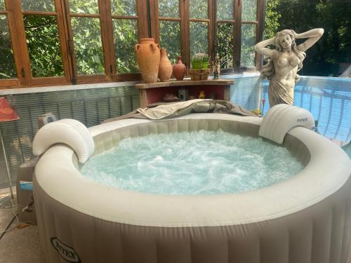 a hot tub with a statue of a woman in it at Chambre campagnarde in Roquestéron