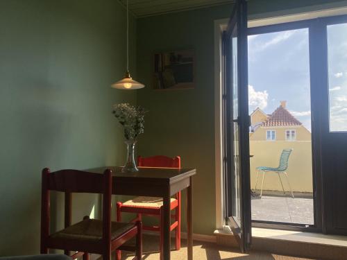 a dining room with a table and chairs and a window at Løkkenshus Rooms and Apartments in the Heart of Løkken in Løkken