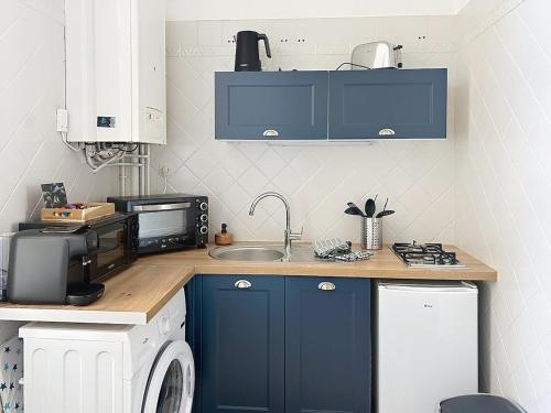 a kitchen with blue cabinets and a sink at Le Léandre - Spacieux et central in Compiègne