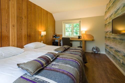 a bedroom with a large white bed and a desk at Landgoedhotel Woodbrooke Barchem in Barchem