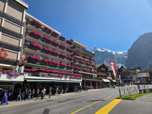 un gran edificio con gente caminando por una calle en Hotel Bernerhof Grindelwald, en Grindelwald