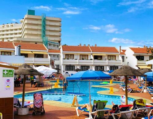 una piscina con sedie e ombrelloni in un resort di Apartamento cerca playa San Eugenio a Costa de Adeje