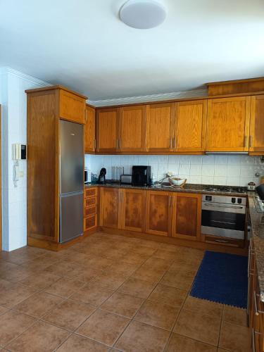 a kitchen with wooden cabinets and a stainless steel refrigerator at Villa Nenúfares in Torreira