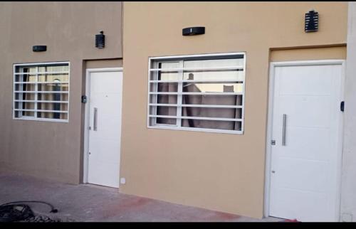 two white doors on a building with windows at Alquiler diario el palmar in Cinco Saltos