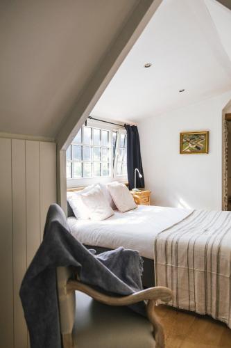 a bedroom with a bed and a window and a chair at Authentieke schuur nabij Brugge in Beernem