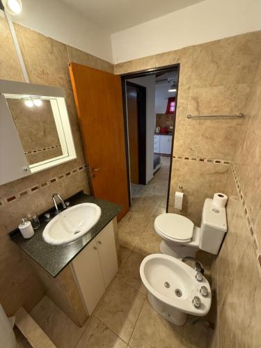 a bathroom with a sink and a toilet and a mirror at Departamento cerca del centro - Carhue in Villa Carlos Paz