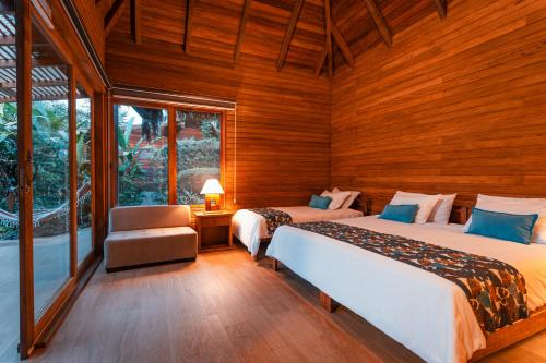 two beds in a room with wooden walls and windows at El Jardin Lodge & Spa in Puerto Misahuallí