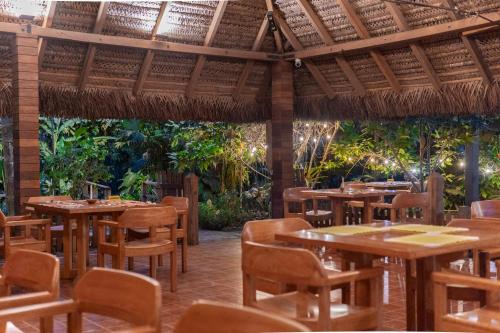 a restaurant with wooden tables and chairs and trees at El Jardin Lodge & Spa in Puerto Misahuallí