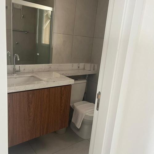 a bathroom with a sink and a toilet and a mirror at Apartamento confortável – perto do centro de Bauru in Bauru
