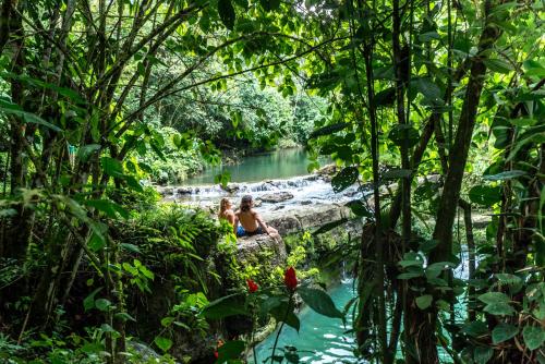 two people sitting on a rock in a river in the jungle at El Jardin Lodge & Spa in Puerto Misahuallí