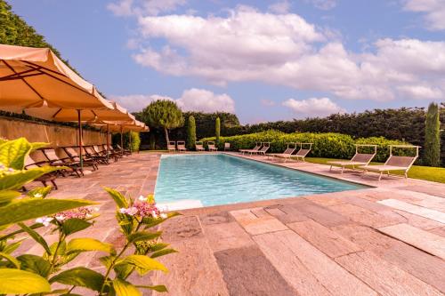 a swimming pool with chairs and umbrellas at Villa Bricco dei Cogni in La Morra