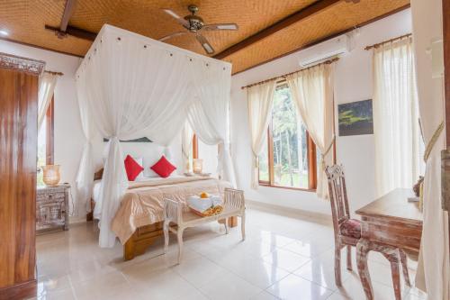 een slaapkamer met een hemelbed met rode kussens bij Villa Mangku in Ricefield in Ubud