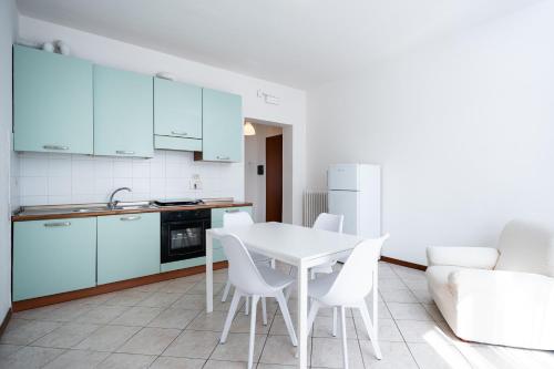 a kitchen with a white table and white chairs at I Due Olivi - Assisi Living in Castelnuovo