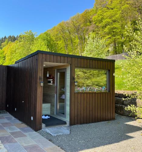 a wooden shed with a glass door in a yard at Relax-Bollendorf in Bollendorf