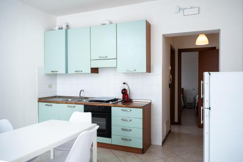 a kitchen with blue cabinets and a white refrigerator at I Due Olivi - Assisi Living in Castelnuovo