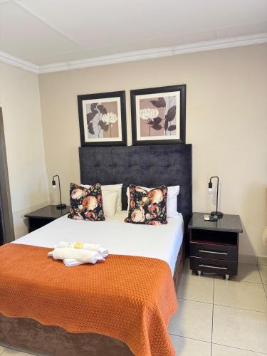 a bedroom with a large bed with an orange blanket at Masana Hotels in Polokwane