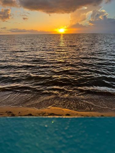 a sunset over the ocean with a beach at Beachfront villa with Direct Ocean Access Sleeps 12 in Cabo Rojo