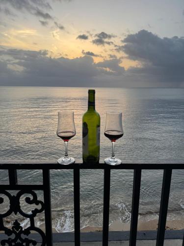 a bottle of wine and two glasses on a rail with the ocean at Beachfront villa with Direct Ocean Access Sleeps 12 in Cabo Rojo