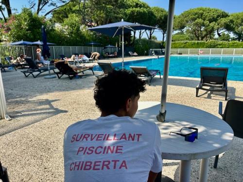 a man sitting at a table in front of a pool at Studio Design Chic à Chiberta - plage & green in Anglet