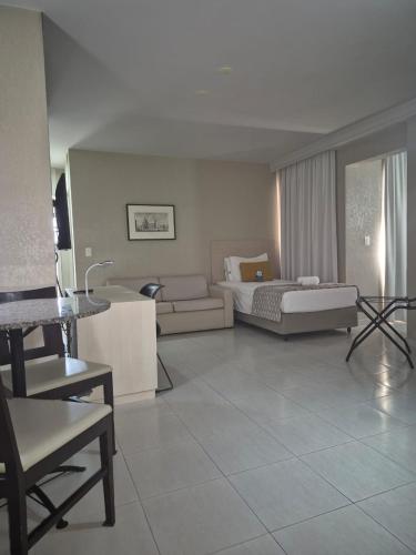 a hotel room with a bed and a living room at Hotel Metrópole Maringá in Maringá