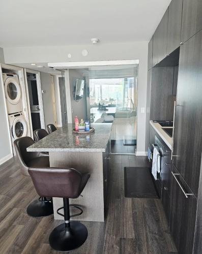 a kitchen with a counter and a bar with chairs at Elegant 2BR & 2BA Retreat in Prime Yorkville, Downtown in Toronto