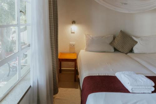 a small bedroom with a bed and a window at Hotel Uhland in Windhoek