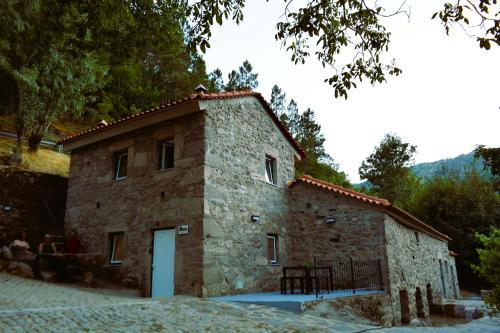 a small stone building with a white door at Moinho do Zorrão in Manteigas
