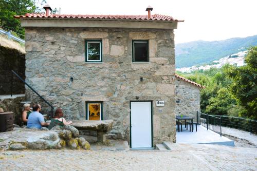 two people sitting outside of a stone building at Moinho do Zorrão in Manteigas