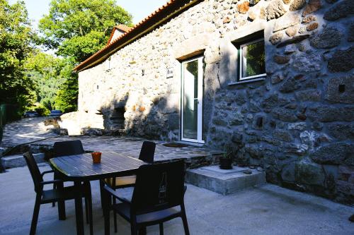 a table and chairs in front of a stone building at Moinho do Zorrão in Manteigas