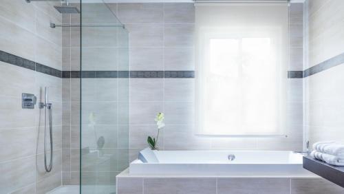 a bathroom with a tub and a shower with a window at Spacieuse villa de vacances avec piscine privée in Souraïde