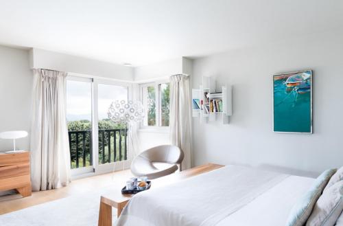 a bedroom with a bed and a chair and a window at Spacieuse villa de vacances avec piscine privée in Souraïde