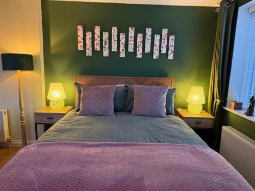 Un dormitorio con una cama con una pared verde. en The Stables @ The Forge Cronk Y Voddy, en Saint Johns