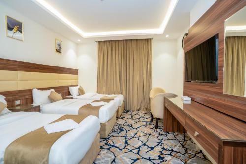um quarto de hotel com duas camas e uma televisão em فندق منازل المقام em Al Khansāk