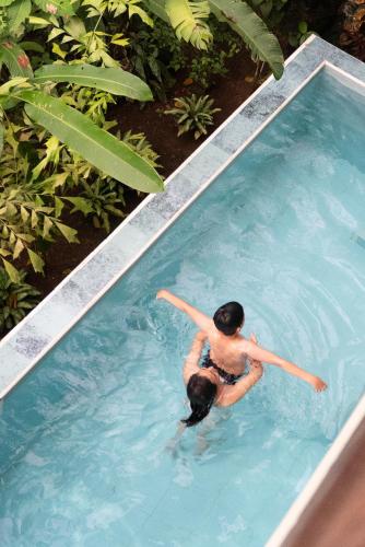 a man swimming in a swimming pool at El Jardin Lodge & Spa in Puerto Misahuallí