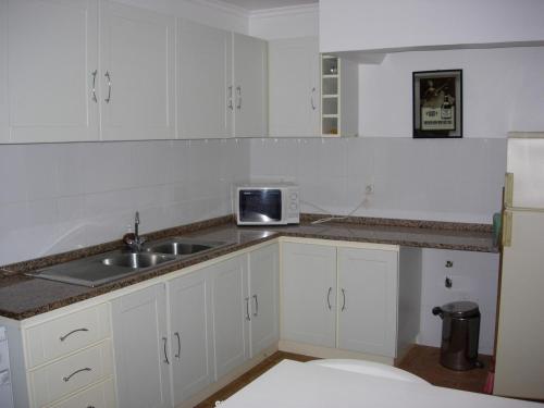 una cucina con armadi bianchi e lavandino di Hostel Casal São João a Ribeira Brava