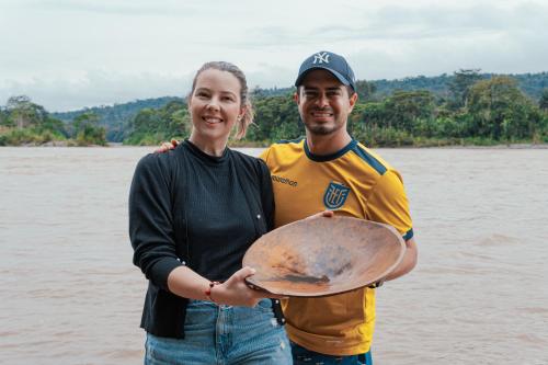 a man and a woman holding a tray in front of a river at El Jardin Lodge & Spa in Puerto Misahuallí