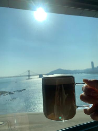 a person holding a cup of coffee in a window at All New Diamond House in Busan