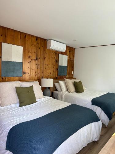 Dos camas en una habitación con paredes de madera. en Cozy Private Room in DTLA, en Los Ángeles