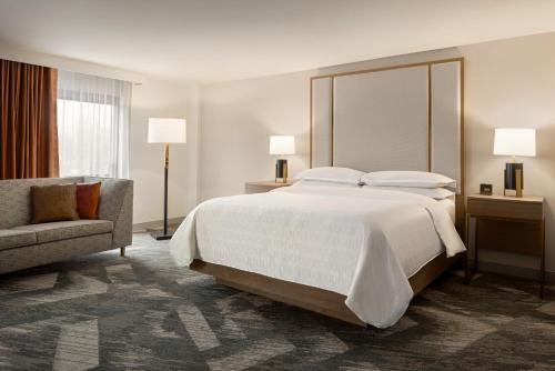 a hotel room with a large bed and a chair at Madison Marriott South in Madison