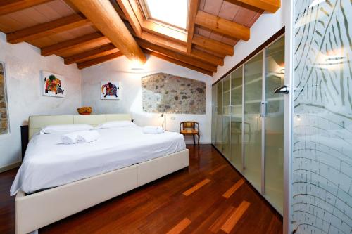 a bedroom with a large white bed and a glass shower at Appartamento BULIAN I in Pozzolengo
