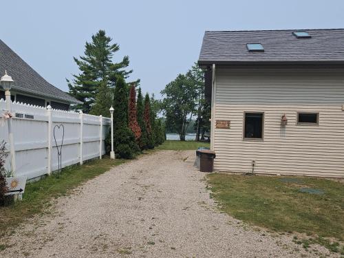 a dirt road next to a white fence next to a house at Marcia Lee Lake House in Suttons Bay