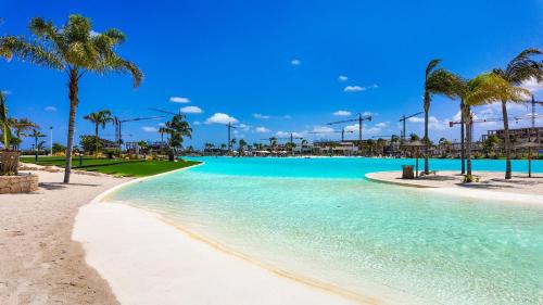 a swimming pool with palm trees and a beach at Villa Palmera in Las Casicas