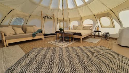 a room with a bed and a couch in a tent at My Little Swan Camping & Camper Stop, Ludbreg in Ludbreg