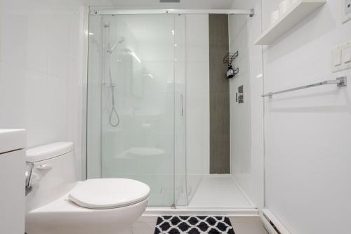 ein weißes Badezimmer mit Dusche und Toilette in der Unterkunft Modern Heritage Stay Upscale 2BR in Old Port in Montreal
